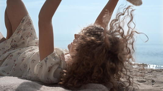 放松的女孩用草帽遮住脸躺在沙滩上视频的预览图