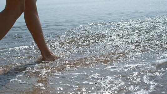 年轻女孩的脚在海浪上跳跃视频的预览图