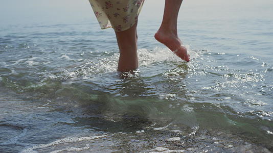 年轻妇女在海水中摔倒拿着帽子视频的预览图