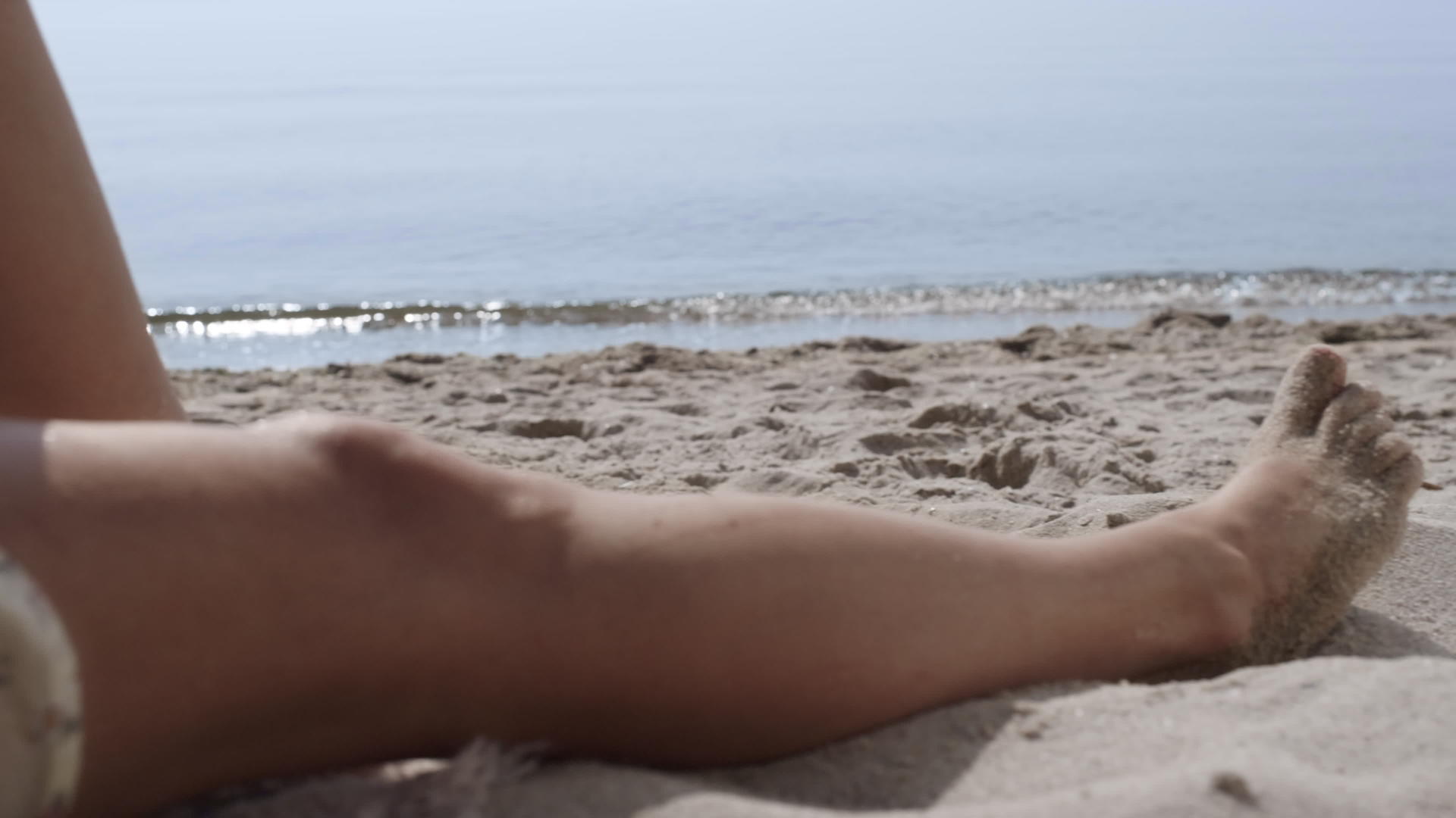 晒黑的女人腿躺在沙滩上身上沾满了沙子视频的预览图