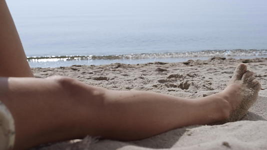 晒黑的女人腿躺在沙滩上身上沾满了沙子视频的预览图