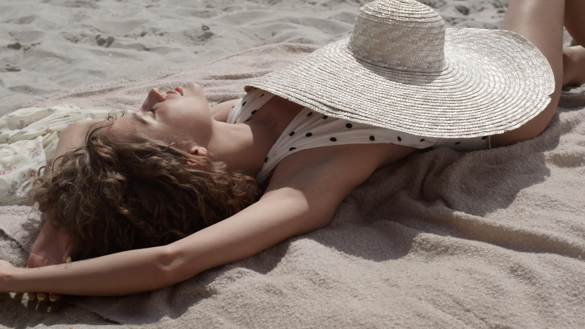 放松的女孩闭上眼睛在沙滩上晒日光浴视频的预览图