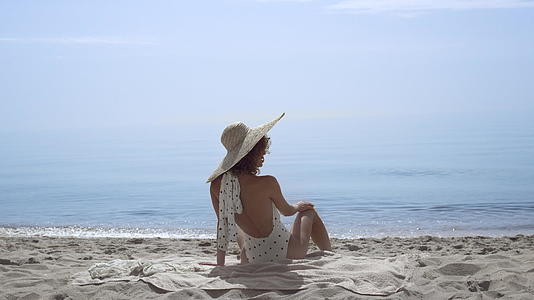 诱人的女人坐在沙滩上穿着泳装在美丽的海浪前视频的预览图