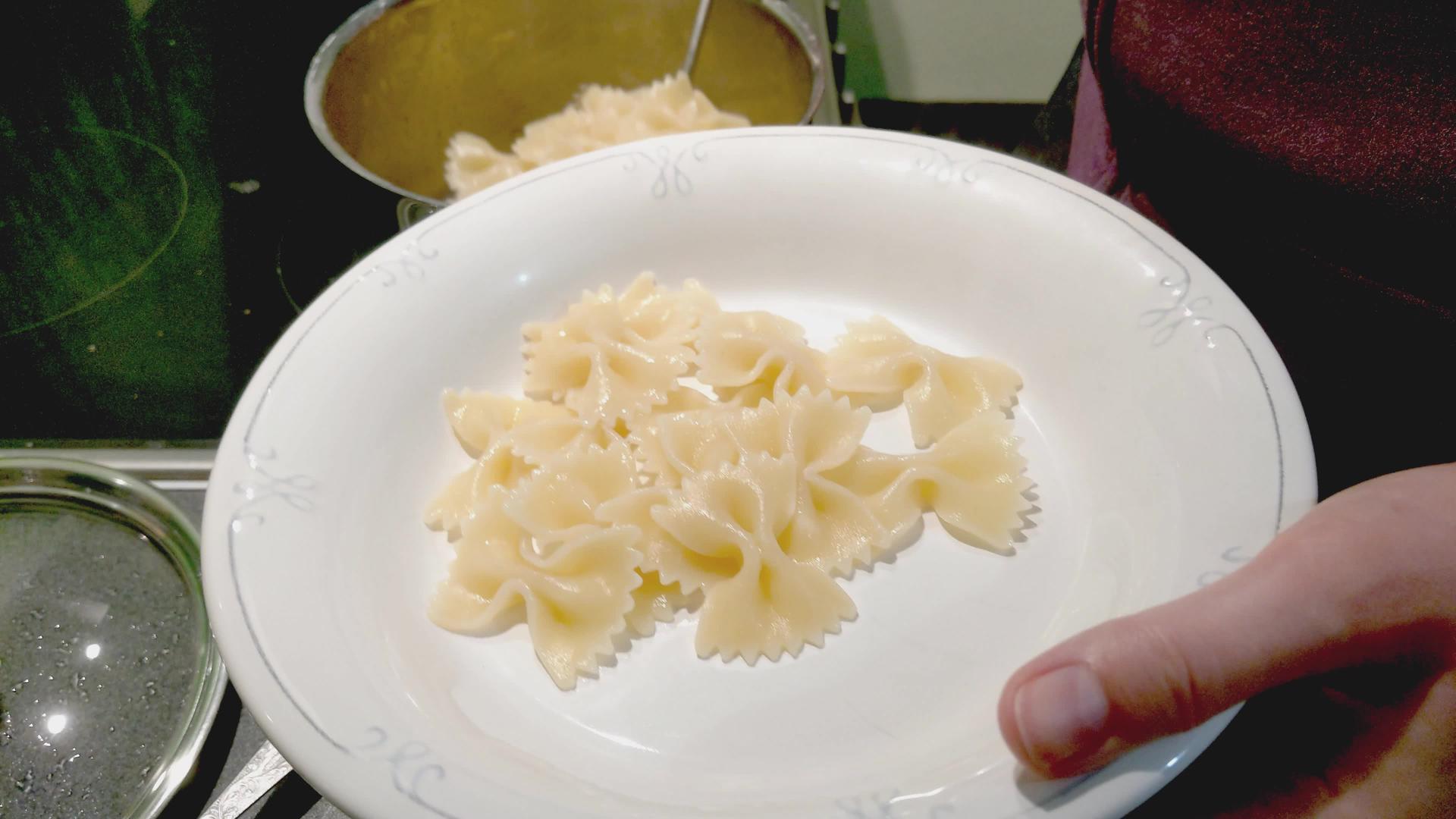 女孩把煮熟的意大利面放在盘子上视频的预览图