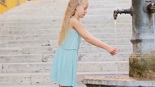 可爱的女孩在意大利夏日街上喝水视频的预览图