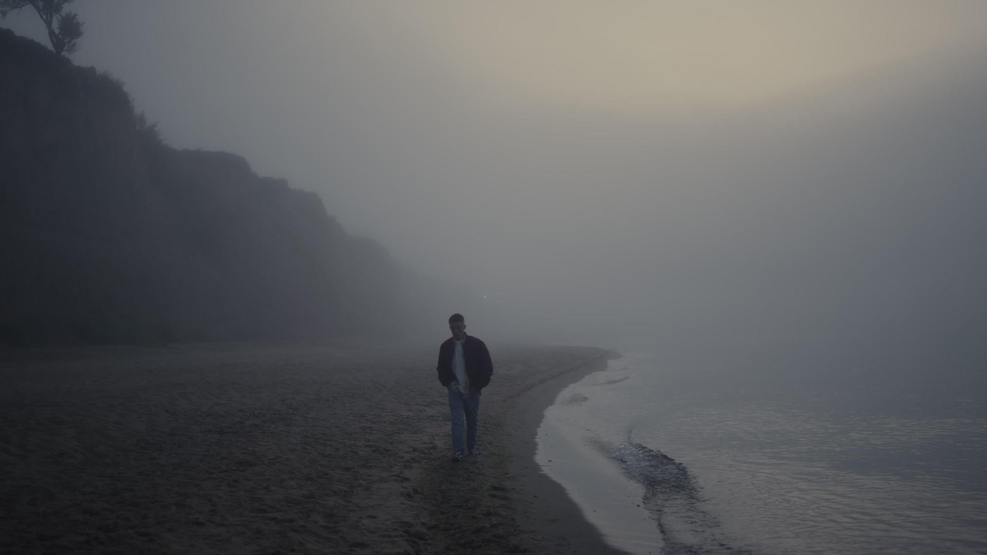 孤单的人在雾天早晨在沙滩上散步视频的预览图