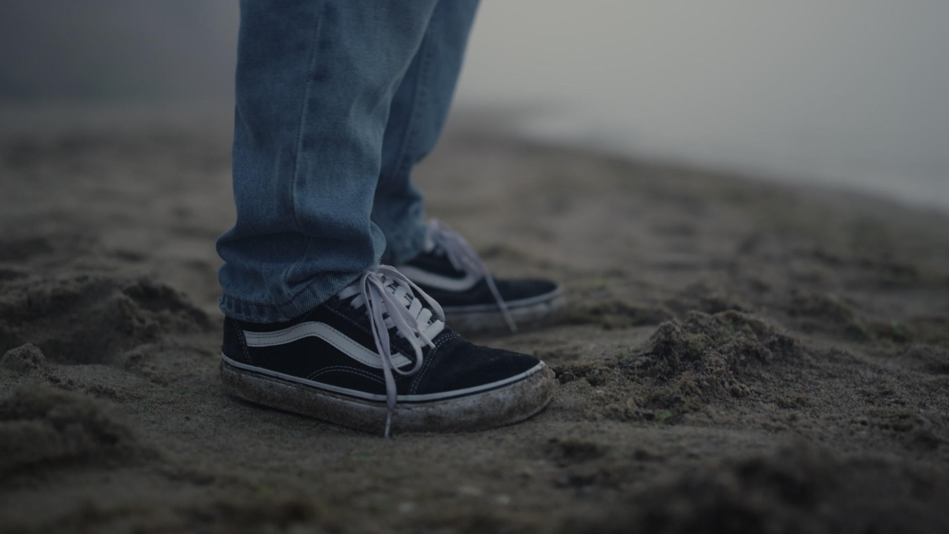 时髦的家伙运动鞋站在沙滩上视频的预览图
