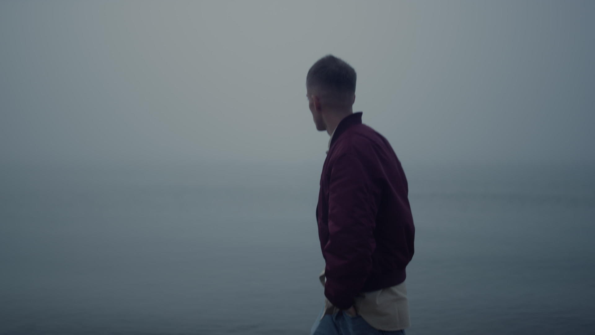 一个悲伤的家伙在雾蒙蒙的早晨走在海边视频的预览图