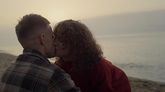 浪漫的夫妇在日出时在沙滩上亲吻视频的预览图