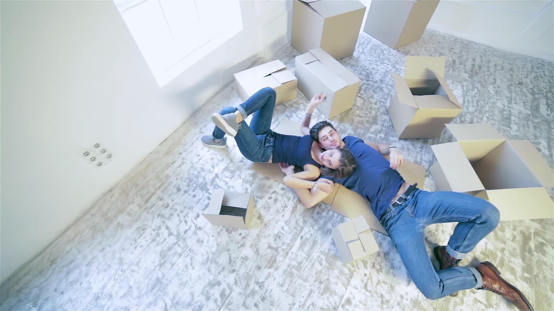 一对夫妇躺在空荡荡的公寓的箱子里视频的预览图