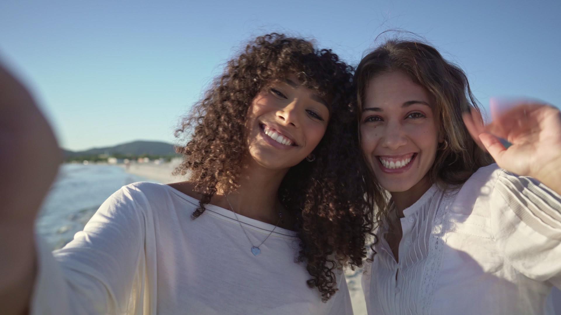 两个可爱的年轻女性在度假期间在海边打视频电话时拥抱—视频的预览图