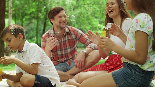 四口之家快乐时光在树林里野餐吹泡泡视频的预览图