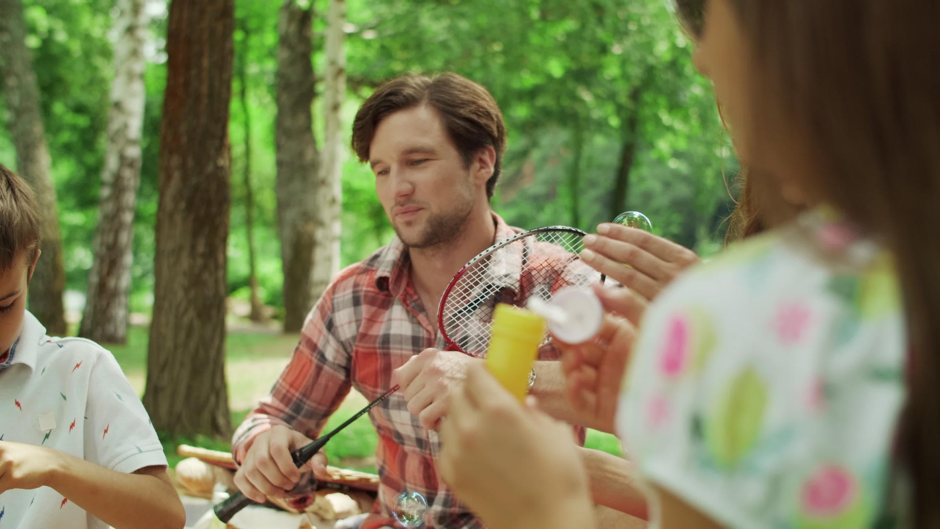在公园野餐的家庭男孩吹泡泡视频的预览图