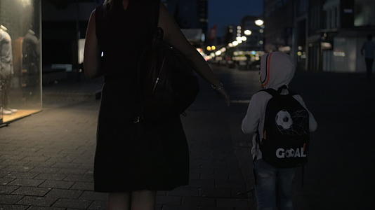 女人的慢动作幻影和儿子在夜空行人街上走来走去视频的预览图