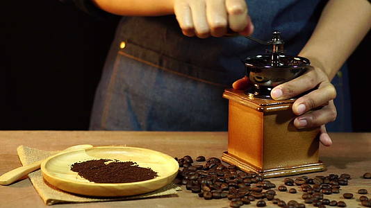 慢动作的女人在木桌上磨咖啡豆视频的预览图