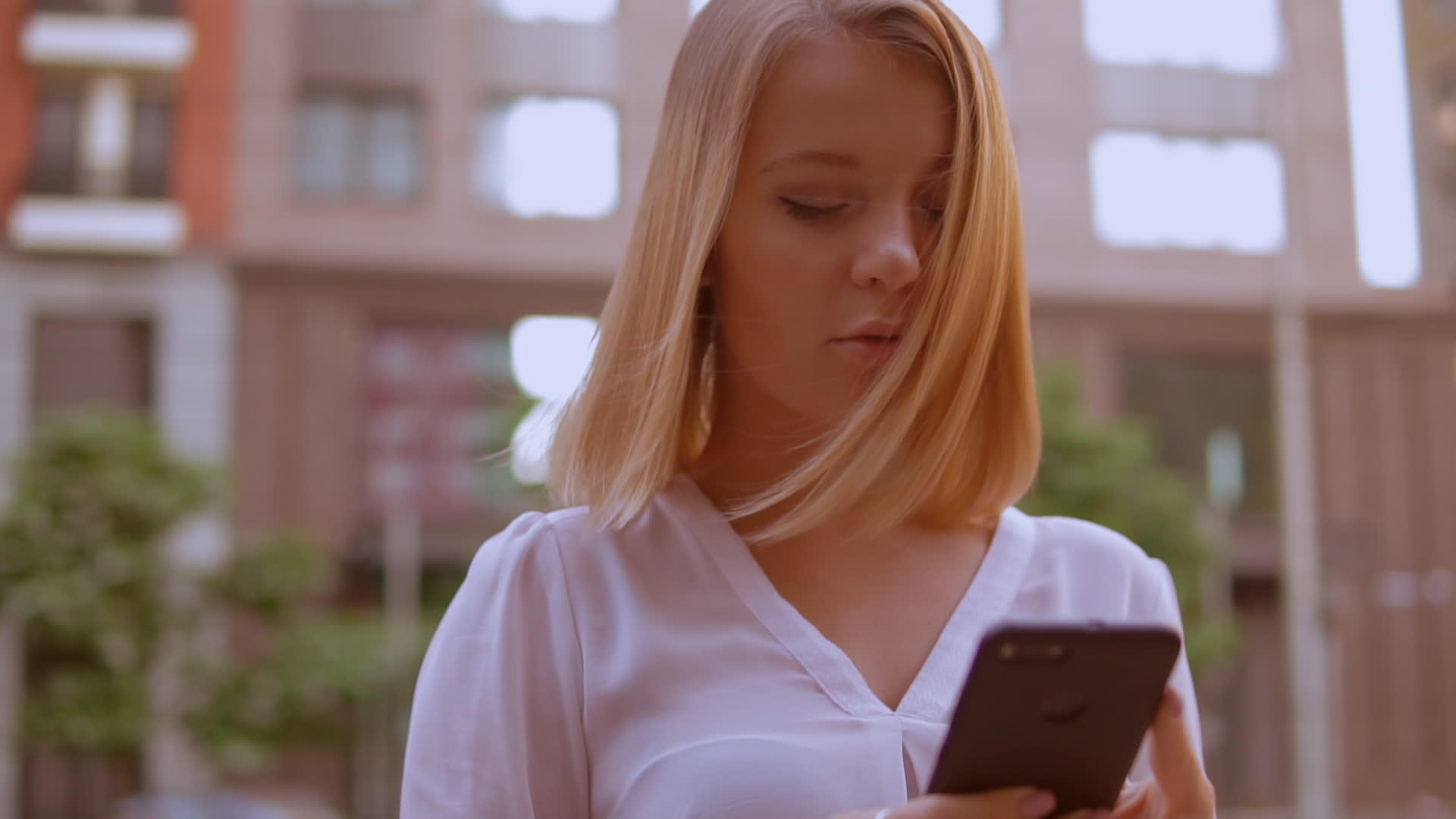 面对金发年轻女性使用智能手机视频的预览图