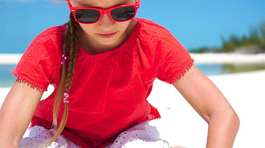 暑假期间海滩上可爱的小女孩的肖像快乐的孩子们玩沙子慢动作视频的预览图