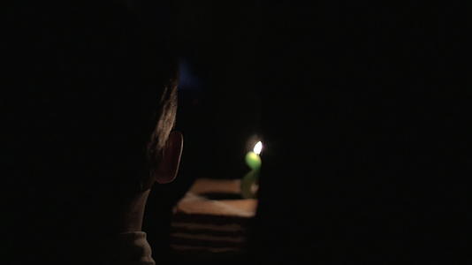 孩子和母亲在黑暗中带着生日蛋糕和蜡烛视频的预览图