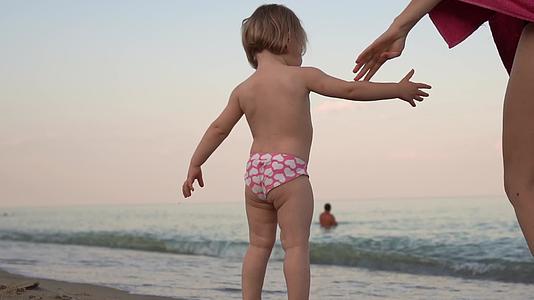 小女孩的母亲站在海滩上看着海浪带走了孩子的家人视频的预览图