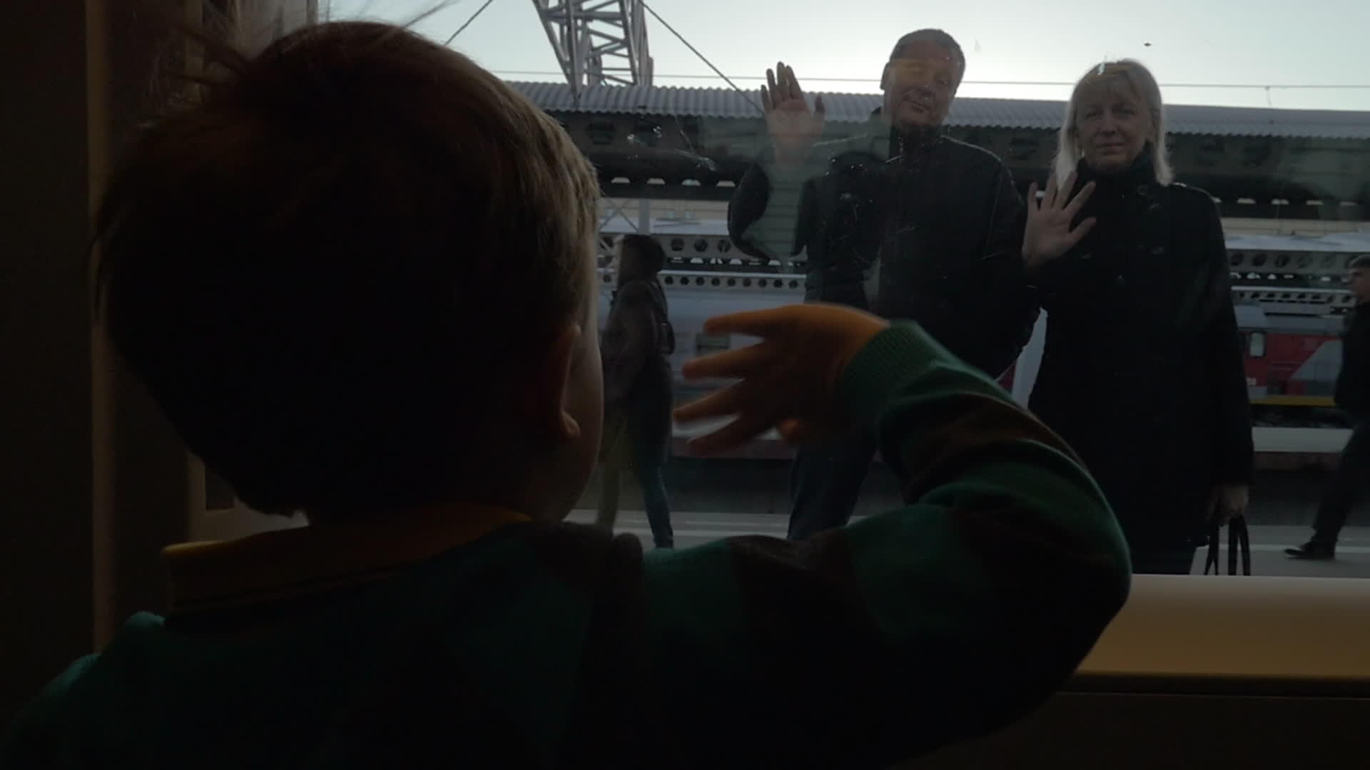 男孩看着男孩在火车窗口慢慢移动然后向他的祖父母走去视频的预览图