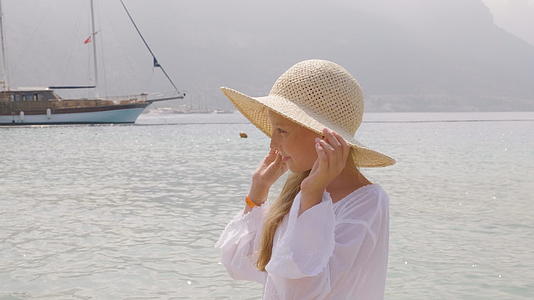 肖像女孩戴着草帽看着海和船美丽的女孩用手拿着视频的预览图