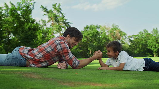 父亲和儿子躺在田野的草地上视频的预览图