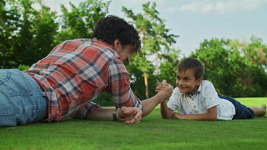 父亲和儿子在草地上练习摔跤视频的预览图