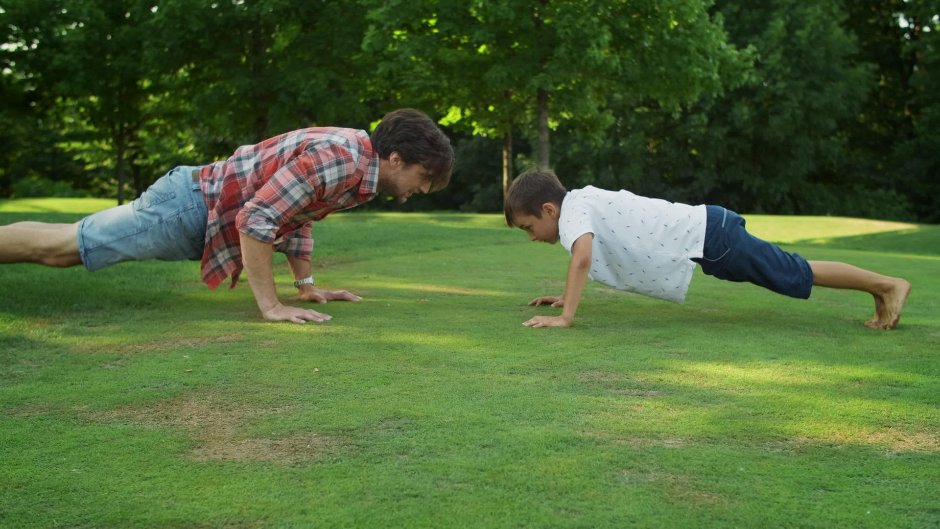 父亲和儿子在公园里做俯卧撑视频的预览图