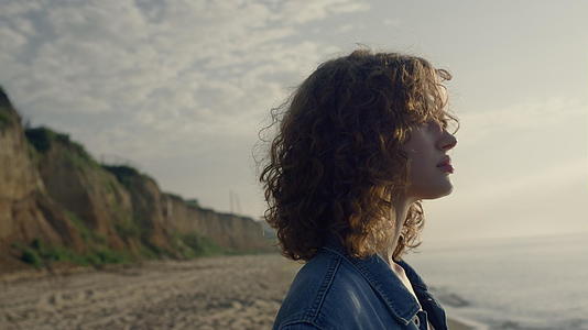 卷发女人在日出时环顾海洋景观视频的预览图