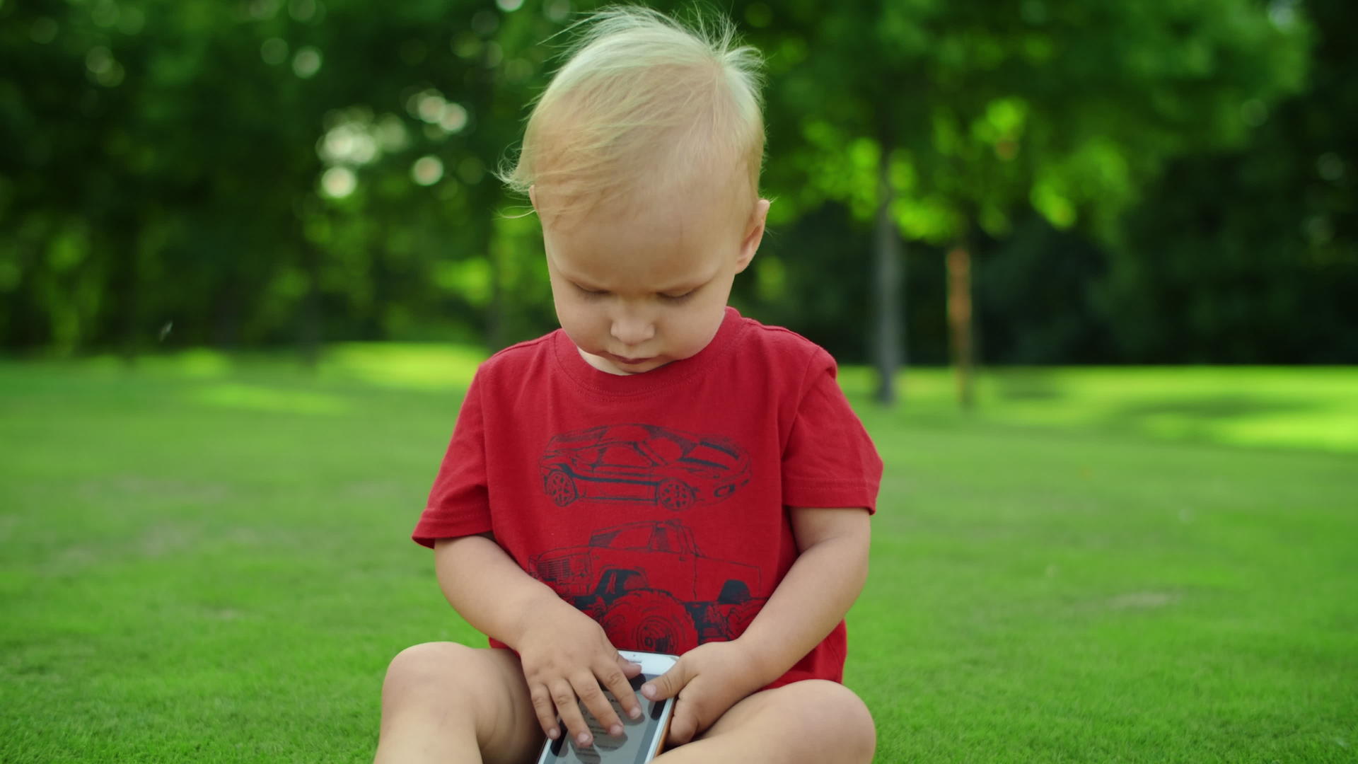 可爱的孩子们坐在绿色的草地上手持机器视频的预览图