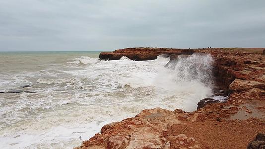 波光粼粼的海浪和岩石海浪溅在海岸上岩石上的海浪粉碎了泡沫视频的预览图