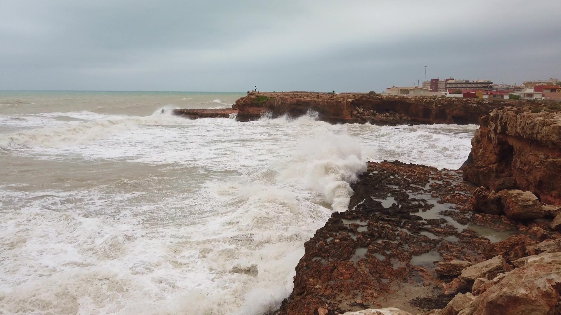 沿着海岸线直冲高山岩石的巨浪视频的预览图