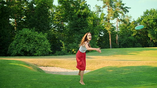 女人在绿草地上玩飞盘视频的预览图