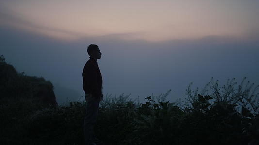 悲伤的男人剪影 站在山顶上 视频的预览图