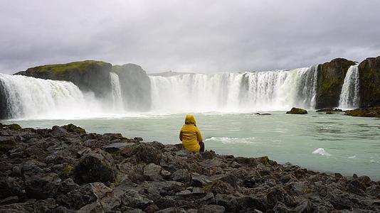 黄色外套游客在冰原的哥达福斯瀑布上放松视频的预览图