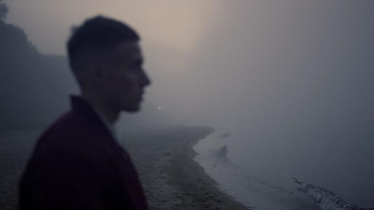 严肃的人在晨雾中行走在海边视频的预览图