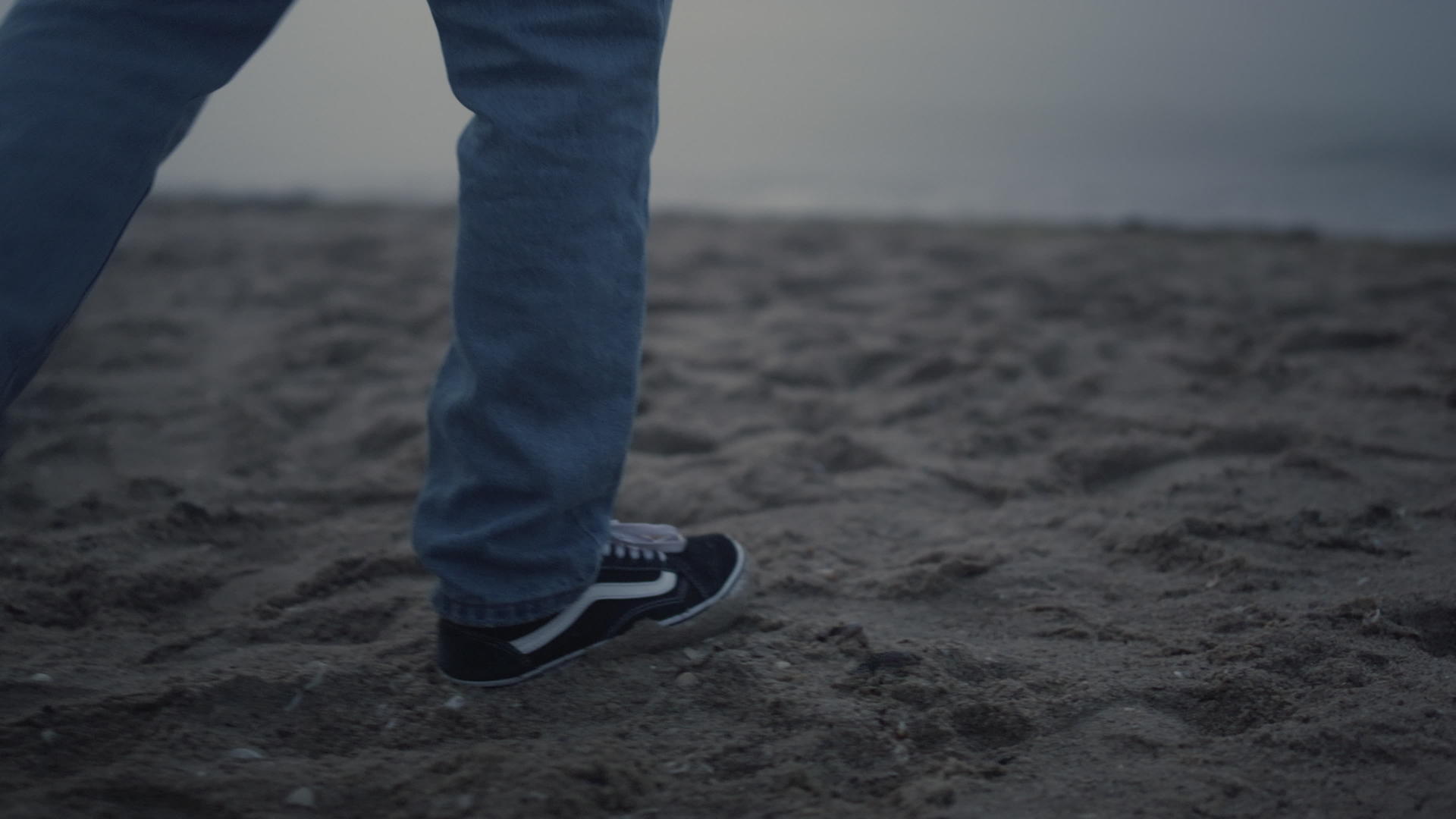 穿着时髦运动鞋走在沙滩上的家伙腿视频的预览图