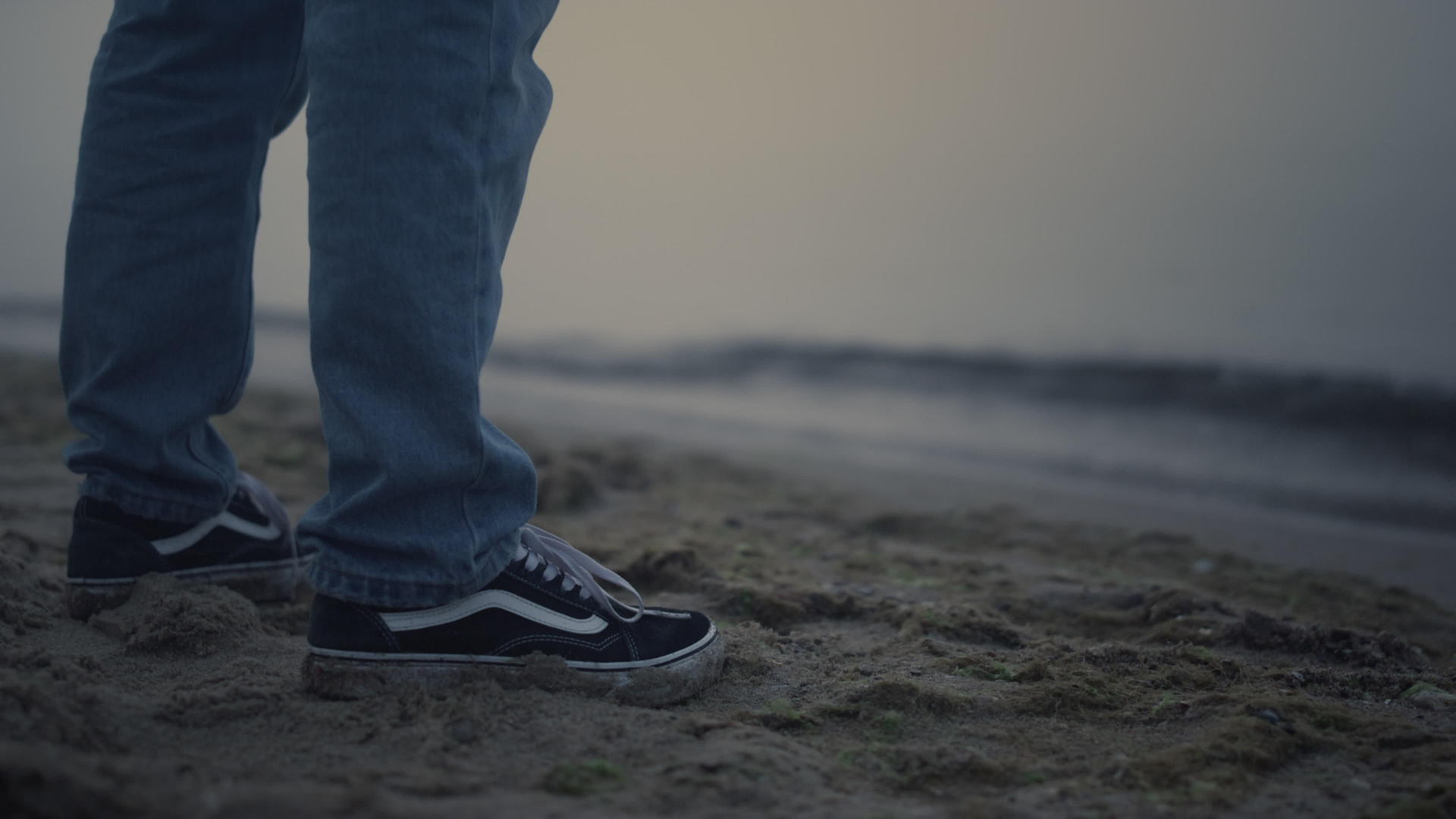 男人穿着运动鞋站在海边视频的预览图