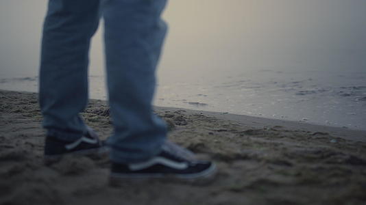 家伙腿运动鞋站在沙滩上视频的预览图