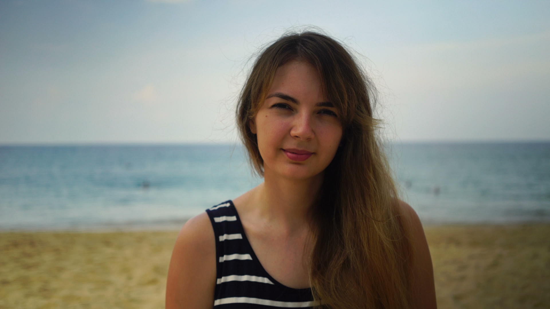 一个年轻的女孩看着海滩上的近视肖像视频的预览图