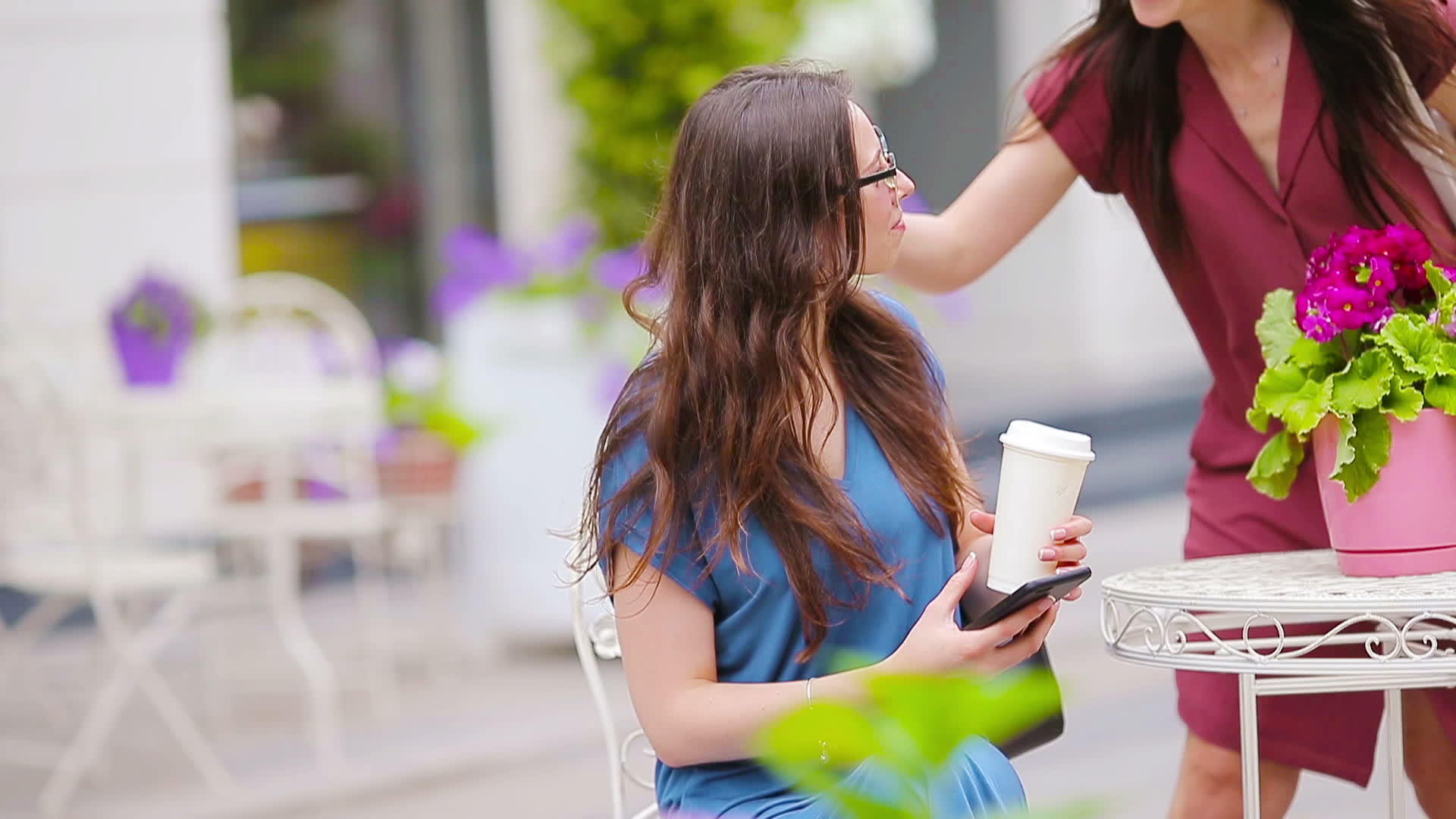 美丽的女人坐在户外咖啡馆喝咖啡用智能手机画像视频的预览图