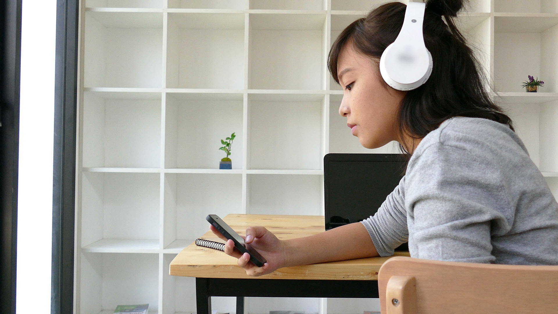 使用耳机佩戴耳机和在智能手机上听音乐的年轻女青年学生视频的预览图