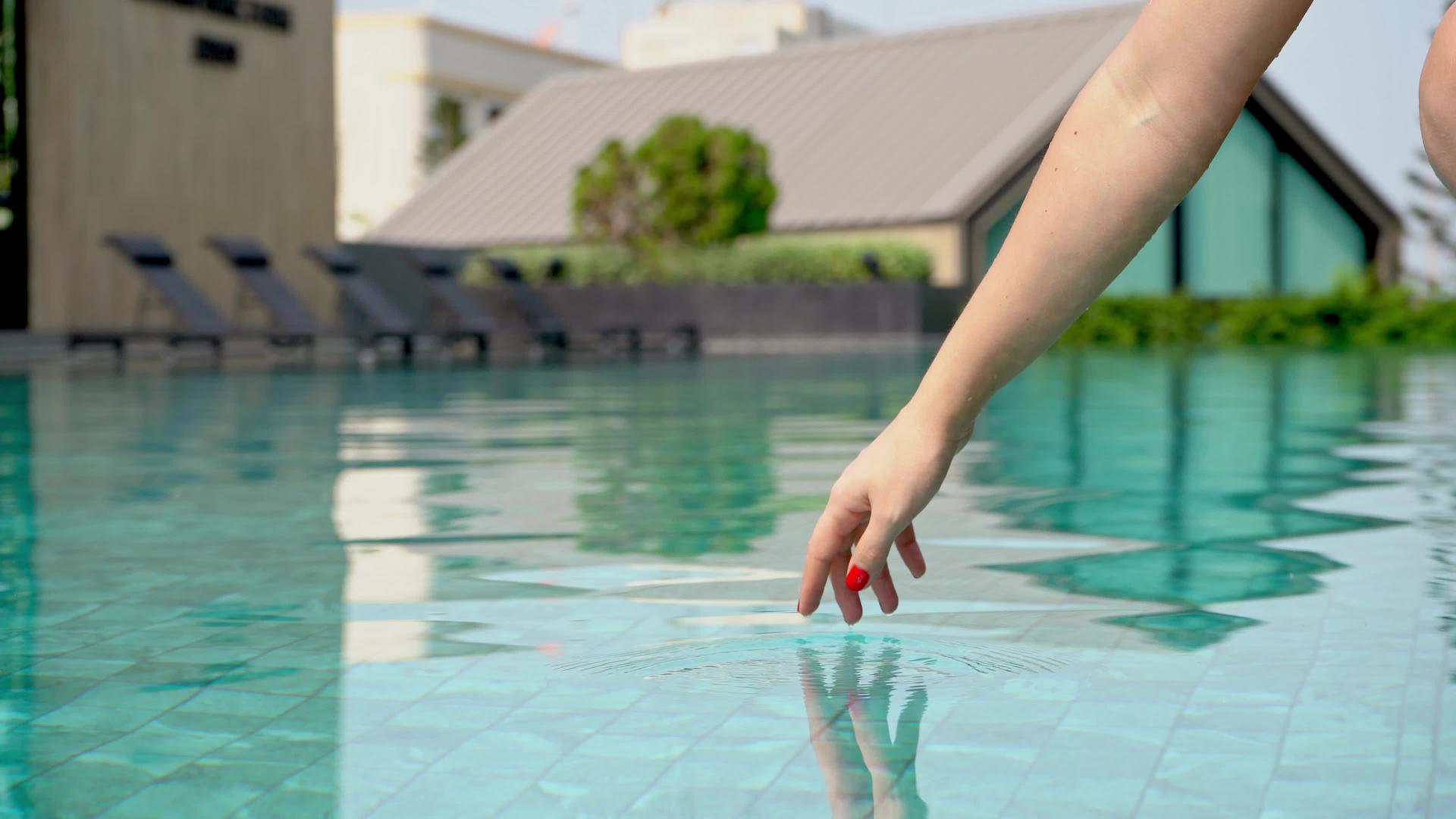 女孩用指尖轻轻触摸游泳池的水视频的预览图