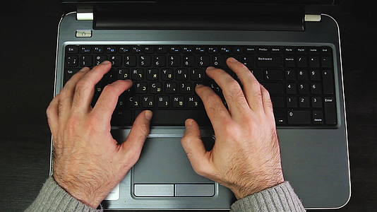 男人在键盘上打字的电影上写着Hebrew和英语字母视频的预览图