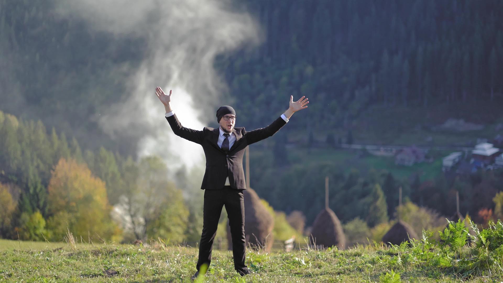 一个穿西装的人在山上举起手视频的预览图