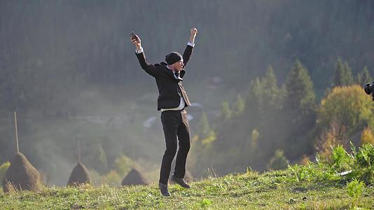 一个穿着漂亮西装的商人在高原上跳跃视频的预览图