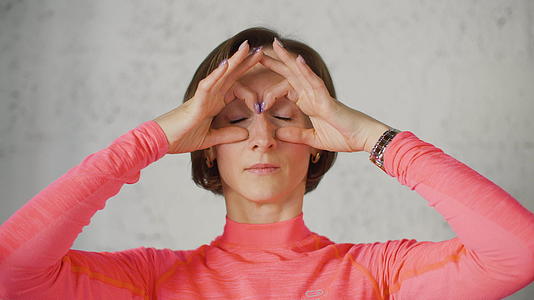 成年女性在面部按摩前置摄像头时用手展示眼镜视频的预览图