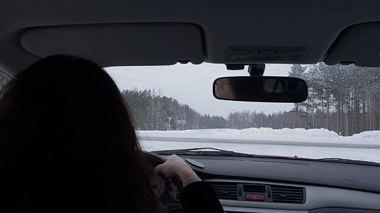 从后座看冬天的风景女人在十字路和雪路上开车视频的预览图
