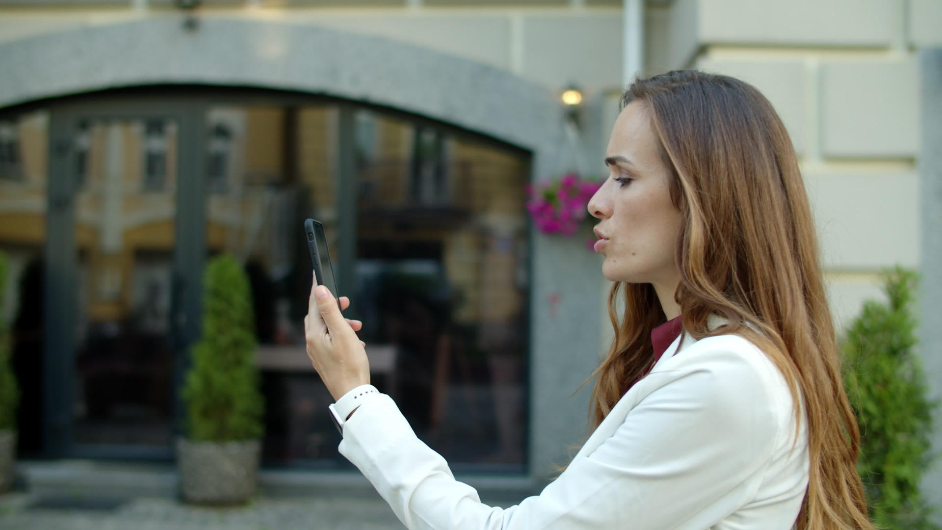 严重的商业女性在户外智能手机在线会议上举行视频的预览图