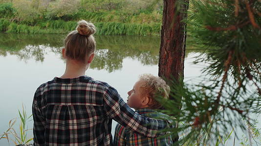 成年姐姐在松树林的河岸上拥抱她哥哥快乐的年轻女孩和男孩视频的预览图